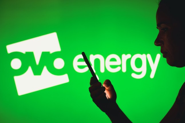 March 30, 2023, Brazil. In this photo illustration, a woman's silhouette holds a smartphone with the OVO Energy logo in the background; Shutterstock ID 2281907657; purchase_order: -; job: -; client: -; other: -
