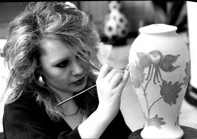 Woman painting a ceramics pot.